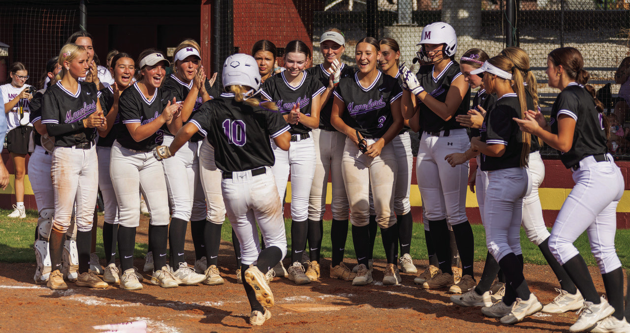 Mannford Lady Pirate Bella Gilbert is welcomed home by the team after hitting a home run out of left field. Photo by John Burns.