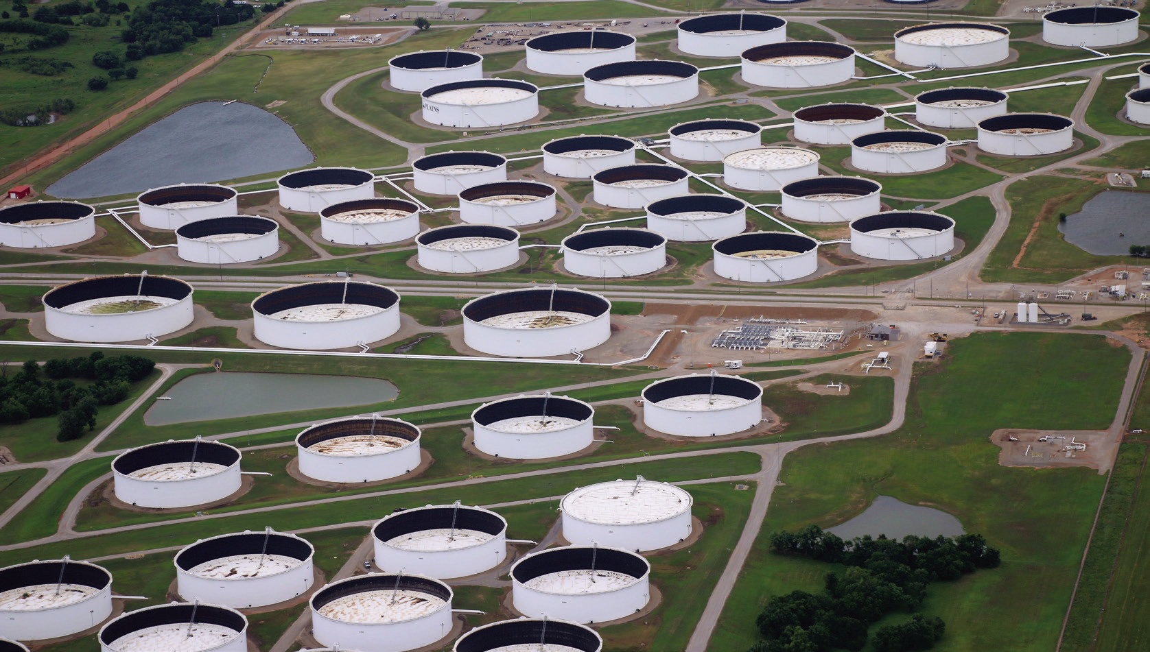 Oil storage tanks at the Cushing hub sit at low capacity. Each tank has a floating lid that rises and falls with the oil inside, allowing observers to estimate the tank’s inventory by the lid’s position. A lower lid indicates less oil in storage. Photo by Caleson Coon.