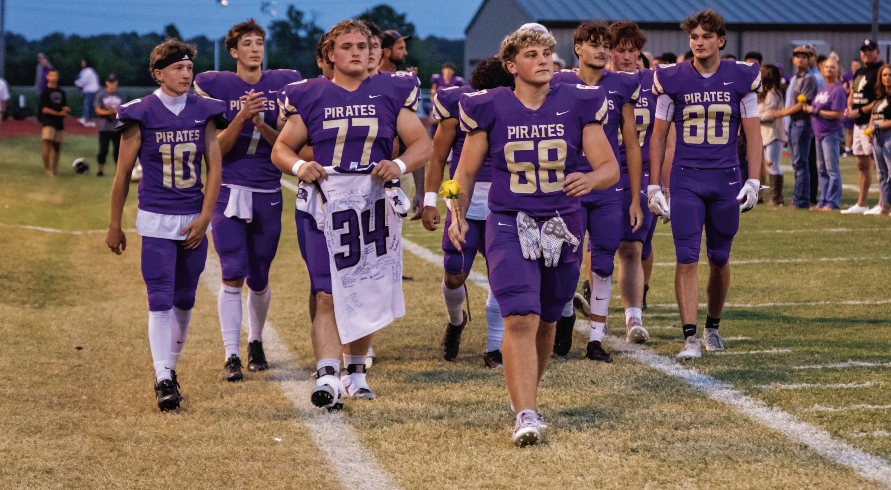 Mannford Pirate Seniors Ricky Morgan, Max Moore, Kendal Howard, Bobby Blackburn, Jarrett Robinson, Sebaschyn Gaches, Rodrigo Esparza, Luke Colson, Nick Hockersmith, Hagen Anderson, Even Thomas, Trey Scott and Braiden Rodriguez, walk down to the 34 yard line of Pirate Stadium Thursday to pay tribute to their fallen teammate, #34 Leland Geary. The Pirates won one for Leland, defeating Victory Christian 48-14. See story, Page 6.