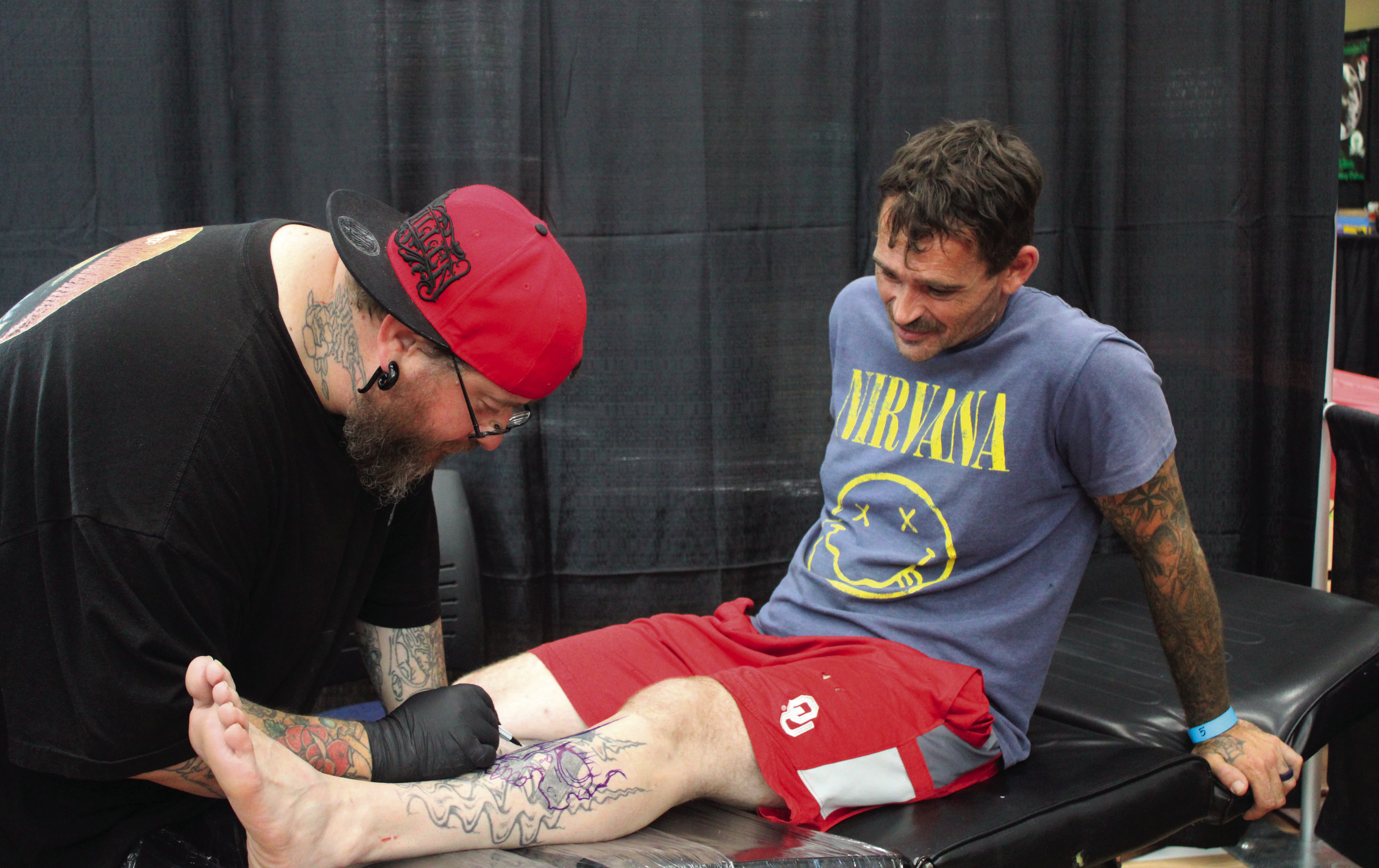 Tattoo artist volunteer Brian Spitz sketches a cover up for Lonnie Bentley. Photo by Caleson Coon