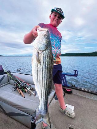Jacob Mefford had to put his Crocs in sport mode for this monster Striper, caught this past weekend at Keystone Lake. Photo by Jeremiah Mefford