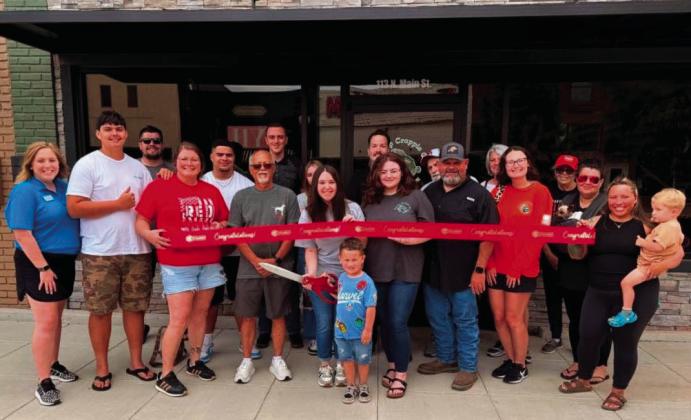 Amanda Wion, Sand Springs Chamber of Commerce, joins other chamber members, well wishers and family of owner Donnie Carter as they celebrate Friday’s grand opening of Thump Crappie, at 113 N. Main Street in Downtown Sand Spring. The store offers crappie fishing tackle, rods, apparel and accessories from its downtown Sand Springs storefront.