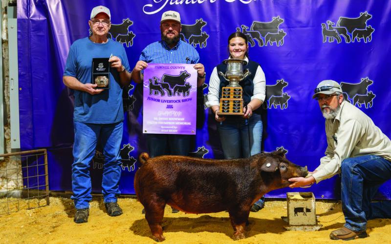 Jacob Thompson stands beside Ryan Brady and Brent Draper as Averi Draper holds her Duroc hog after receiving the Collin Thompson Memorial Showmanship Award — a traveling honor created by Jacob in memory of his son, Collin, a Cleveland FFA showman whose love for the ring still echoes through Pawnee County 20 years later. Photo by John Burns