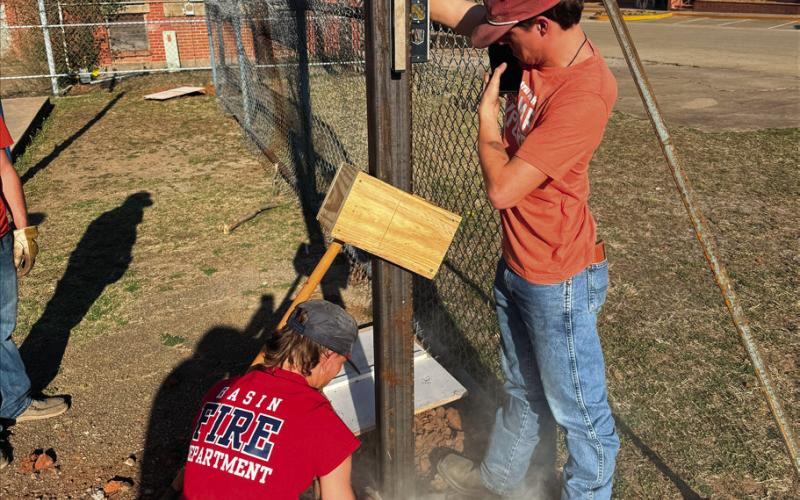 Yale high school student Cayden Lewis and Mannford high school student Peyton Sims levels the first light pole after setting it in the ground and pouring cement.