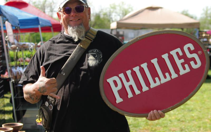 Holding a vintage Phillies sign Kyle Badertscher walks through the Drumright Monthly Market as a satisfied customer. Photo by DeAnna Maddox
