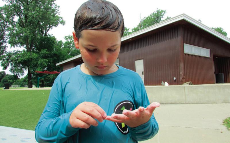 Ledgyn Johns examines his pruning fingers after having spent some time running around the Super Splash Park in Sand Springs’ Case Community Park. Photo by young artist and Ledgyn’s younger cousin Mckale Johns.